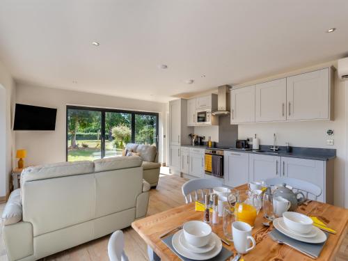 a kitchen and living room with a table and a couch at Cathill Cottage in Creech Saint Michael