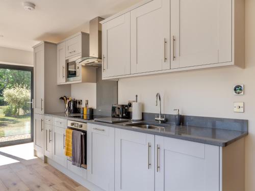 a kitchen with white cabinets and a sink at Cathill Cottage in Creech Saint Michael