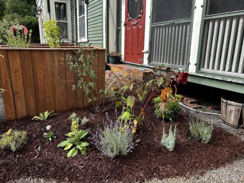 a garden in front of a house with a red door at Garrison House Inn in Annapolis Royal