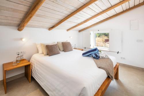 a bedroom with a large white bed and a window at Quinta do Ourives in Carvoeiro