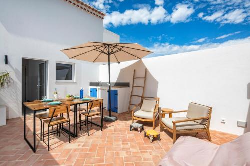 a patio with a table and chairs and an umbrella at Quinta do Ourives in Carvoeiro