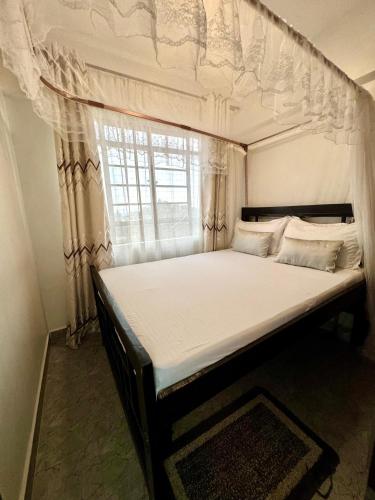 a large bed in a room with a window at Hideout in Kisumu