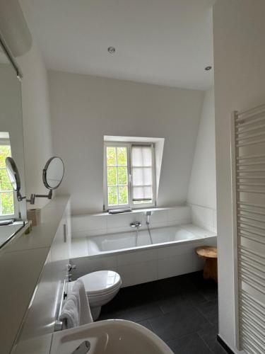 a bathroom with a tub and a toilet and a sink at Six! Eat Work Sleep in Brühl