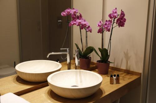 a bathroom with two sinks and flowers on a counter at Residenza Dell' Opera in Turin