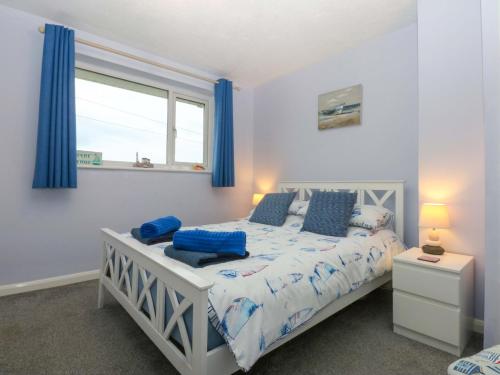 a bedroom with a bed with blue pillows and a window at Pebbles Reach in Colwyn Bay