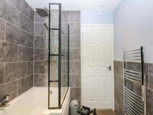 a shower with a glass door in a bathroom at Pebbles Reach in Colwyn Bay
