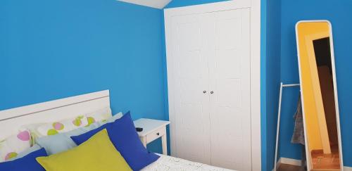 a bedroom with a bed with blue walls and a mirror at Casa familiar katandres in San Mamés de Meruelo
