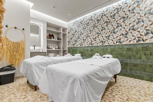 two white tables in a room with a wall at Panarea Beachfront Living - Pools Spa Gym & Luxury Amenities in Bucerías