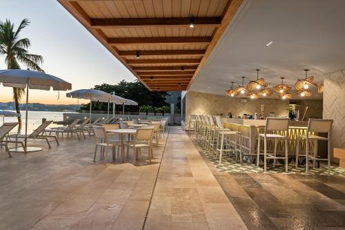 a restaurant with tables and chairs and a bar at Panarea Beachfront Living - Pools Spa Gym & Luxury Amenities in Bucerías
