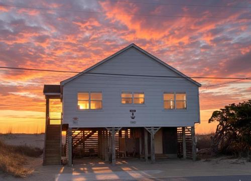 a white house with a sunset in the background at Mitch's Haven - Kitty Hawk MP 2, Oceanfront, 3 Bedrooms, Vintage Charming Cottage in Kitty Hawk