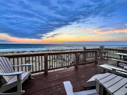 a deck with benches and the beach at sunset at Mitch's Haven - Kitty Hawk MP 2, Oceanfront, 3 Bedrooms, Vintage Charming Cottage in Kitty Hawk