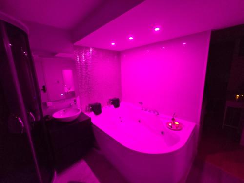 a pink bathroom with a tub and a sink at Spa & Jacuzzi Dupla Privada Escapadinha Romântica Abrantes in Abrantes