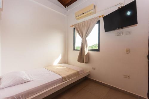 a small bedroom with a bed and a window at Hotel Casa Encanto in Doradal