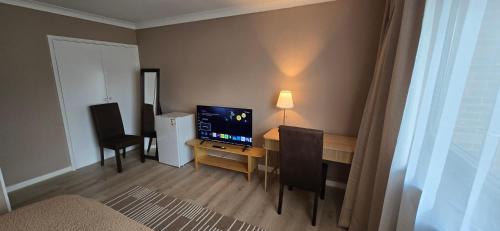 a room with a desk with a television and chairs at Twickenham and West Middlesex Rooms Isleworth Stay in Isleworth