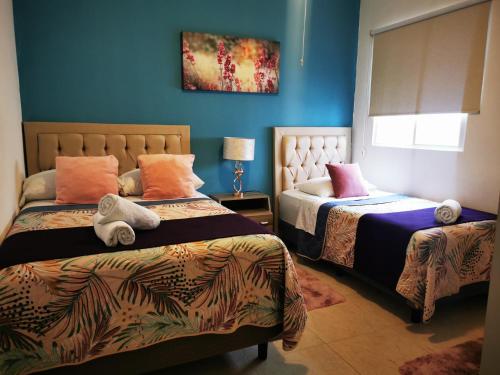 a bedroom with two beds and a blue wall at Apartamento exclusivo piscina, jaccuzi, céntrico. in Cancún