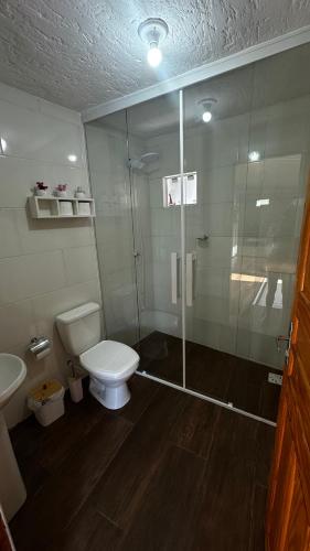 a bathroom with a toilet and a glass shower at Casa com vista para a natureza e piscina in Garopaba