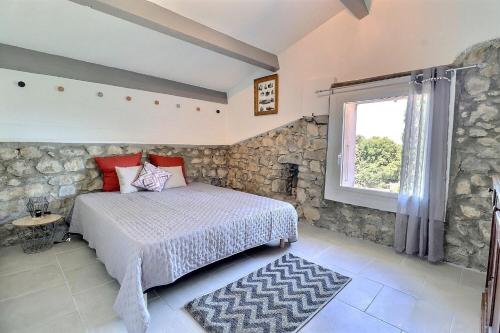a bedroom with a bed and a stone wall at La Rochere in Sampzon