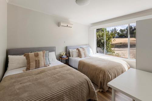 two beds in a room with a window at Nanda Lake House in Bonnie Doon