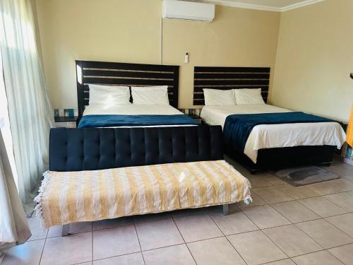a bedroom with two beds and a bench in it at Druza’s guest house in Rustenburg