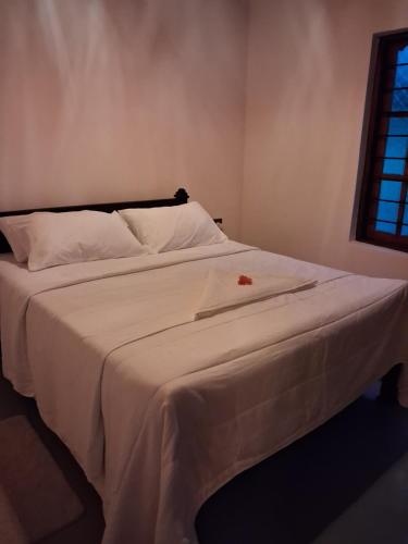 a large white bed with a white sheets and a window at Pasikuda Shalom Echo Villa in Palayadithona