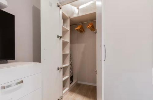 a walk in closet with white cabinets and a television at Little Dream Apartment Sitges in Sitges