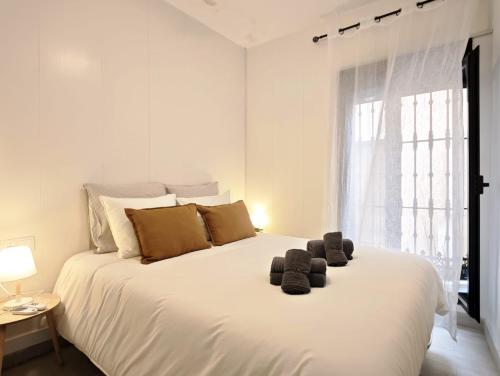 a white bedroom with a large white bed with brown pillows at El Tesoro de Cadiz in Cádiz