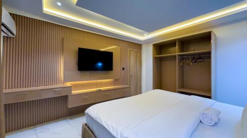 a bedroom with a bed and a tv on the wall at Bayford Suites in Abuja