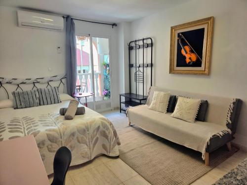a bedroom with a bed and a couch and a violin at Estudio a 5 minutos del Aeropuerto in Torrellano