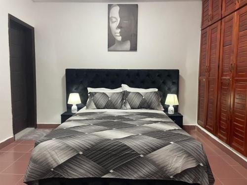 una camera da letto con un letto bianco e nero con due lampade di Residence Nelo a Abidjan