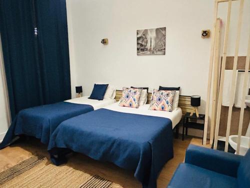 two beds in a hotel room with blue sheets at Monte Sinai Guest House in Porto