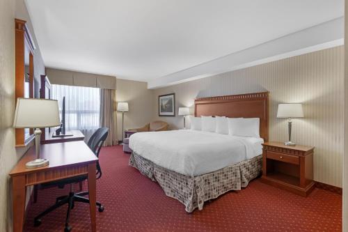a hotel room with a bed and a desk at Best Western Plus Otonabee Inn in Peterborough