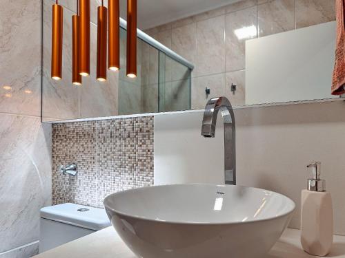 a bathroom with a white sink and orange pendant lights at Apartamento com 2 quartos a 5 minutos do centro in Brusque