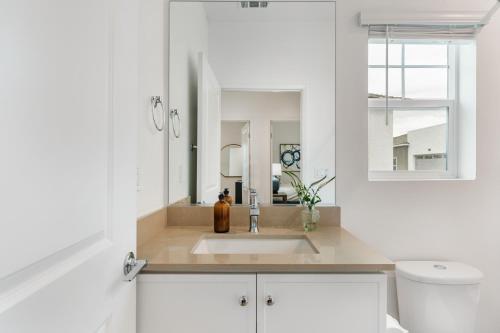 a white bathroom with a sink and a mirror at Summerwell by AvantStay in La Quinta