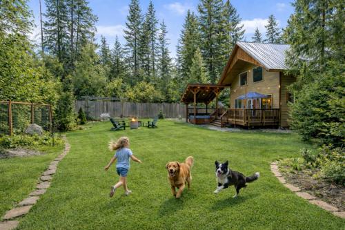 a young girl playing with two dogs in a yard at Paws in the Mountains by NW Comfy Cabins in Leavenworth