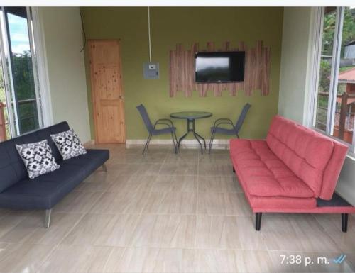 ein Wohnzimmer mit Sofa, Tisch und Fernseher in der Unterkunft Villa Daisy in El Quije
