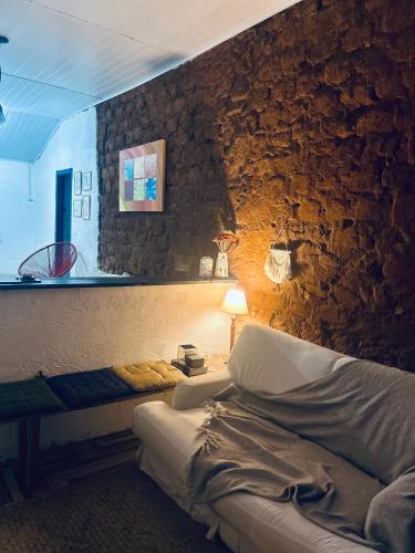 a bedroom with a stone wall with a bed and a lamp at Bendita Pausa-Igatu in Igatu