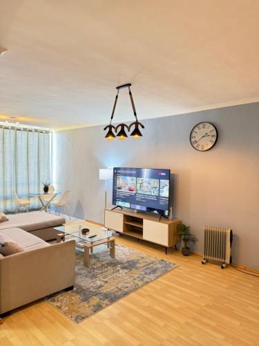 a living room with a couch and a tv and a clock at Cozy Apartment with Table Mountain and beach views in Cape Town