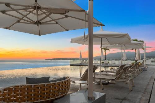 a group of chairs and umbrellas next to the water at UDARA - Beachfront Condos in Golden Zone with Rooftop in Bucerías