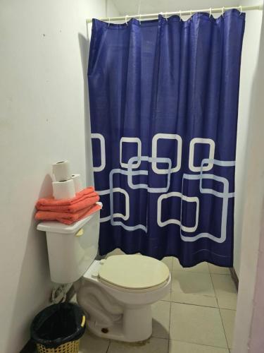 a bathroom with a toilet and a blue shower curtain at Habitación 2 climatizada cerca de IMSS UMAE in Veracruz