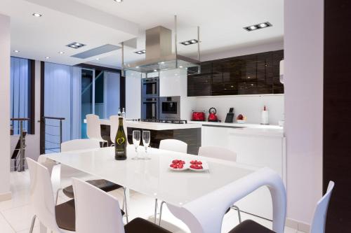 Il comprend une cuisine et une salle à manger avec une table et des chaises blanches. dans l'établissement InStyle Aparthotel, à San Ġiljan