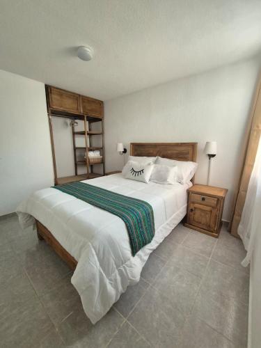 a bedroom with a large white bed and a night stand at Casa Luna TX in Tequisquiapan