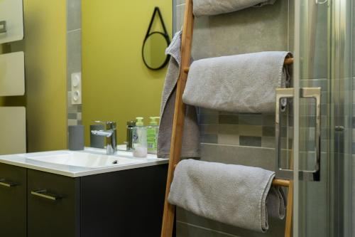a bathroom with a sink and a shower with towels at La petite cour in Beaune