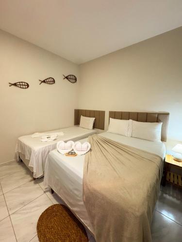 a bedroom with two beds with white sheets and two hats at Pousada Cajueiro Do Sol in Barreirinhas