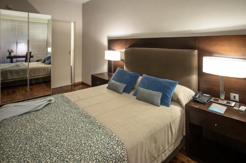 a hotel room with a large bed with blue pillows at Grand Brizo Comahue in Neuquén