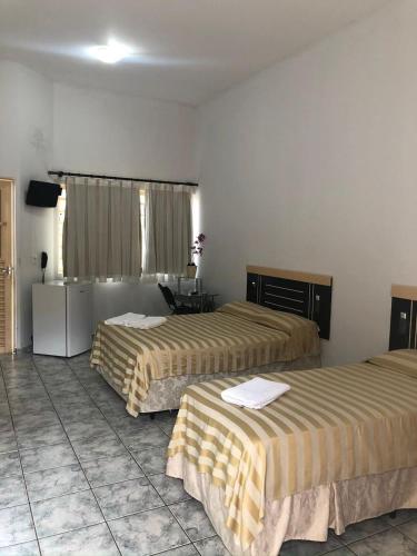 a hotel room with two beds and a desk at Hotel Capim Dourado in Palmas