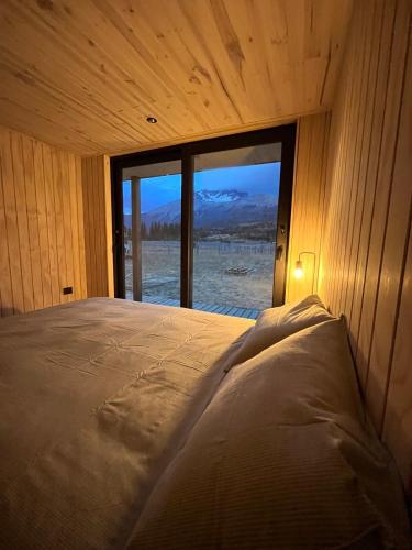 a bed in a room with a large window at Refuge with Panoramic Views, Cerro Castillo in Villa Cerro Castillo