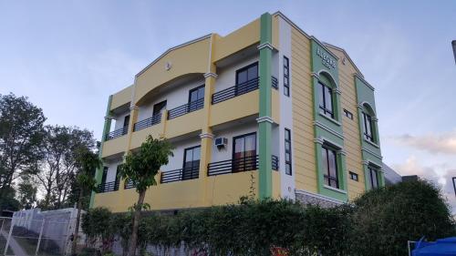 a yellow and green building with a tree at Alegre Building Lipa in Lipa