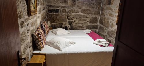 a small bedroom with a bed in a stone wall at Casa da Massada in Belmonte