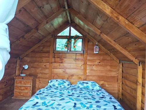 a bedroom with a bed in a wooden room at Eco Cabaña en el Campo in La Vega