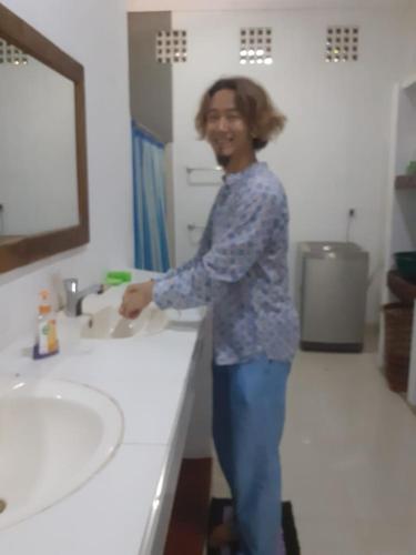 a woman standing in front of a bathroom sink at Pasikuda Shalom Echo Villa in Palayadithona